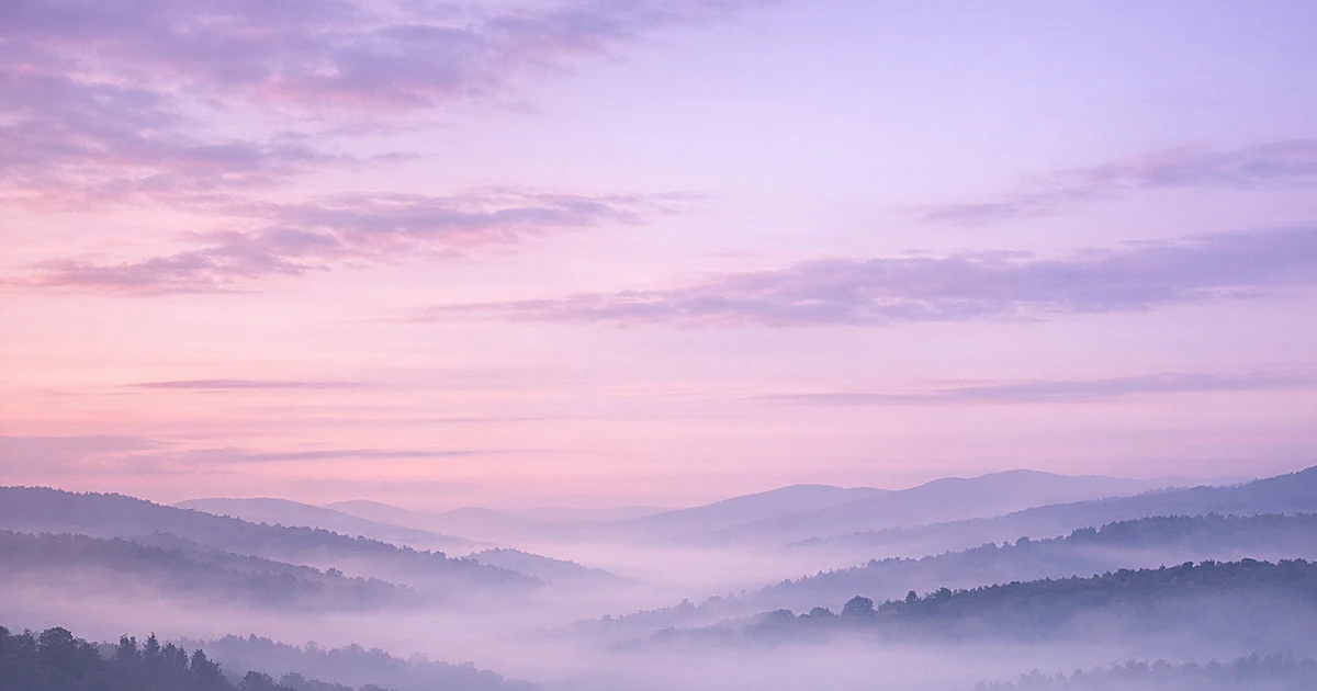 Abstract misty landscape with soft purple clouds fading into gentle dawn light over rolling hills