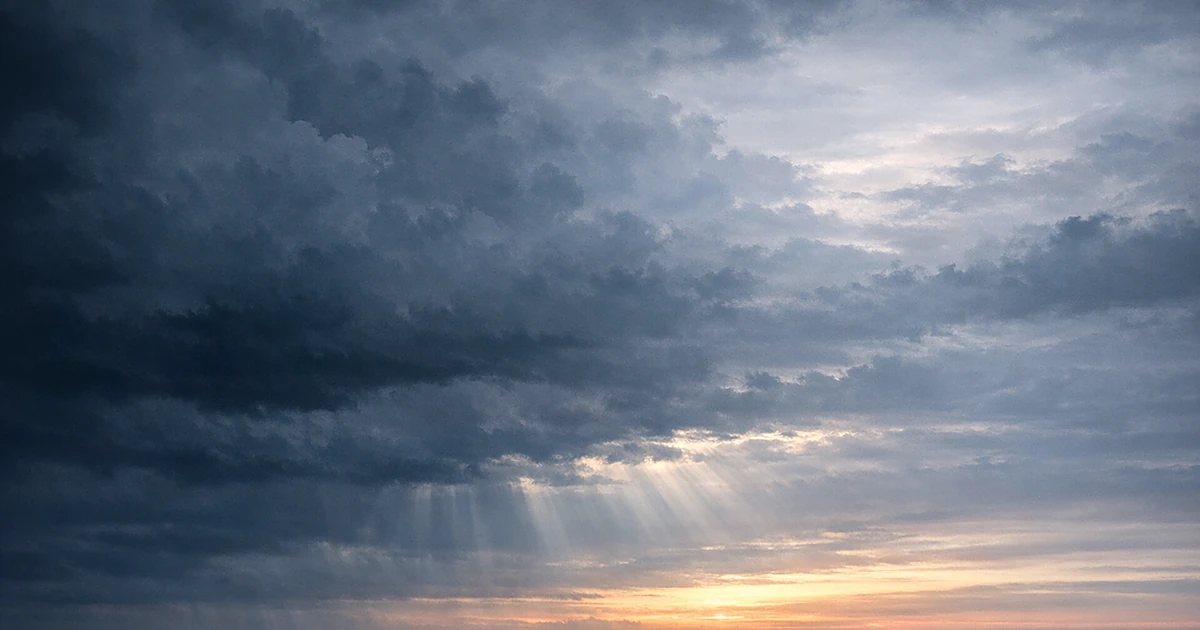 Abstract storm clouds transitioning to dawn light with soft rays breaking through grey and blue atmospheric layers