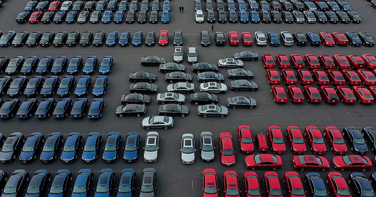 Aerial view of parking lot with blue and red cars in groups, gray cars scattered between representing undecided voters